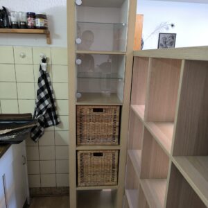 Ikea-Regal mit Vitrieneneinsatz und Flechtkörben