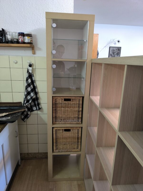 Ikea-Regal mit Vitrieneneinsatz und Flechtkörben